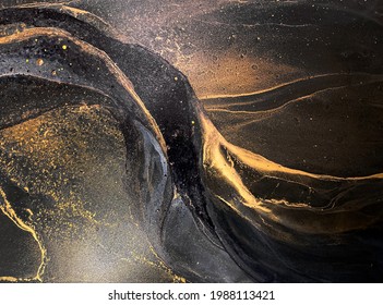 Abstract black art with gold — black background with beautiful smudges, stains and splashes made with alcohol ink. Gold fluid texture resembles space, night sky, stone, smoke, watercolor or aquarelle.