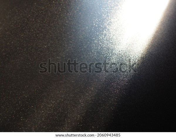 Abstract black background. Oblique light rays on a\
black blackdrop with flickering dots. From right top, the lines are\
directed down and to the left. Glow, flare or shine. Side lighting.\
Small glow