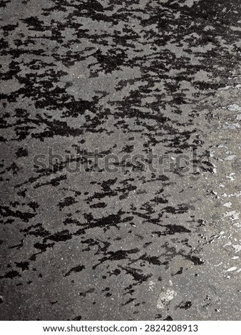 Abstract black patterns on a wet asphalt surface.