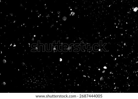 Abstract black and white image of floating translucent bubbles in dark space.