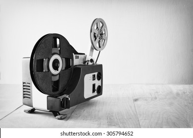 Abstract Black And White Image Of Old 8mm Film Projector Over Wooden Table And Textured Background