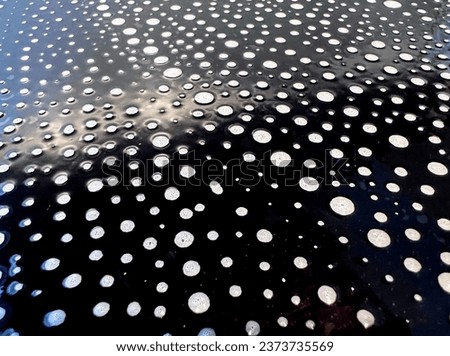Abstract black and white monochrome surface with the soap detergent foam bubble circle dot spots on the shiny black panel background