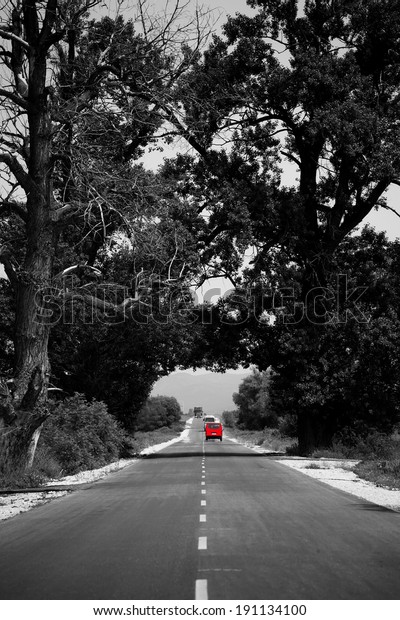 abstract black and white road with single red car in\
distance 
