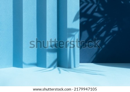 Abstract blue background with shadow of palm leaves for the presentation of a cosmetic product. A scene with a geometric backdrop. Podium for product promotion, beauty, natural eco cosmetic. Showcase.