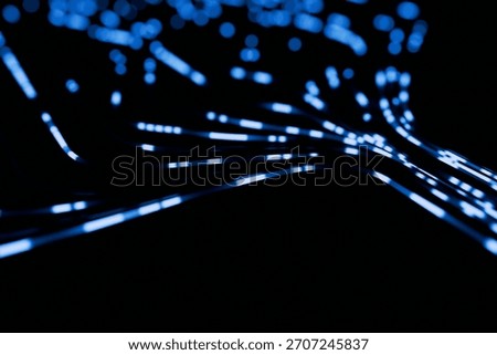 Abstract blue data streams and blurred light particles flowing dynamically across a black background. Concept for fast network, fiber optics, big data transfer, and high-speed technology