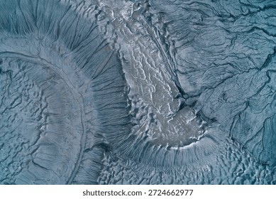 Abstract blue gray mudflow texture with deep cracks and frozen landslide patterns, cold industrial wasteland background aerial top down view