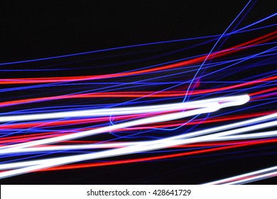 Abstract Blue, White, Red Streaks Of Light On A Black Dark Background Creates A Unique Pattern.