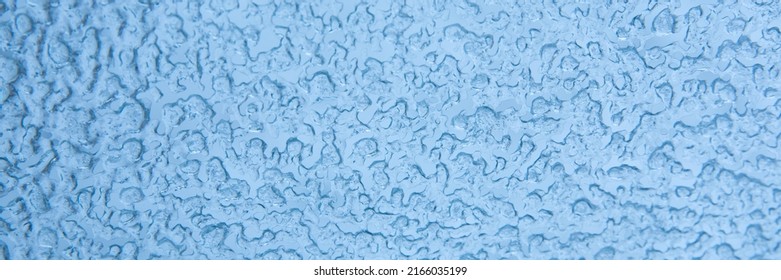 Abstract blue winter background. Texture of frozen water drops, ice surface on the window. Selective focus, web banner