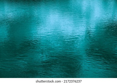   Abstract blue-green background. Reflection of sunlight on the surface of the water. Ripples. Small waves. Teal background with space for design. liquid, fluid.                             