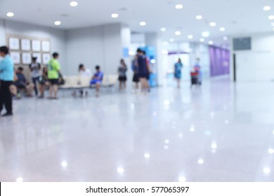 Abstract Blur Background Of Hospital Or Clinic Interior Waiting Hall/ Corridor With Patient People Using Phone And Waiting For See Doctor In Front Nurse Station And OPD.