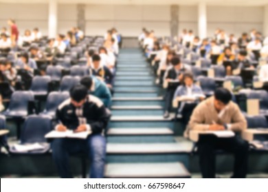 Abstract Blur Background Of Student During Study Or Quiz, Test And Exams From Teacher Or In Large Lecture Room / University Classroom.