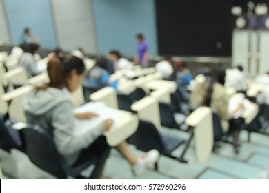 Abstract Blur Background Of Students During Study Or Quiz, Test And Exams From Teacher Or In Large Lecture Room / University Classroom.