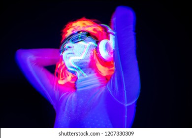Abstract blur of beautiful sexy woman with cyborg UV face paint, wig, glowing glasses, glowing clothing and headphones in front of camera, Half body shot. Asian woman. Party concept.