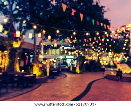 abstract blur image of food stall at night market festival for background usage . (vintage tone)