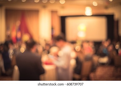 Abstract Blur Long Dinner Table Served As Buffet Stand In Large Banquet Room. Multiethnic People Socializing At Meeting, Conference, Hotel Convention Event. Indoor Catering Food Party. Vintage Tone.