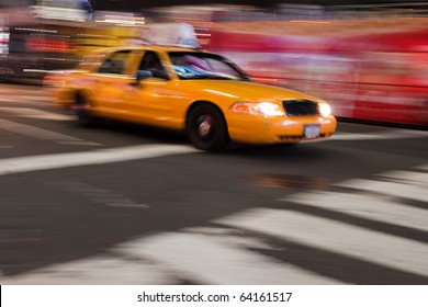 Abstract blur of a night time urban street scene with a yellow taxi cab speeding by.  Slow shutter speed panning technique used for motion blur.