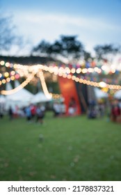 Abstract Blur People In Vintage Day To Night Outdoor Festival In Backyard Green City Park Bokeh Background. Outside Festive, Party And Celebration Concept.