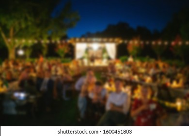 Abstract Blur Of People Watching Outdoor Movie In The Yard. 