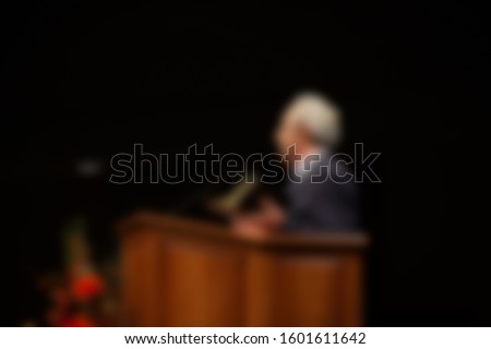 Abstract blur of preacher preaching inside a church from podium. 
