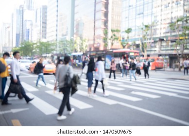 Abstract Blurred Of Asian Busy City People Crowd Walking On Zebra Crossing Street With Modern Building As Background, Korea, Asia