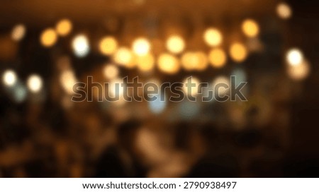 An abstract blurred background features warm golden and amber bokeh lights with soft out-of-focus shapes in a dark indoor environment.