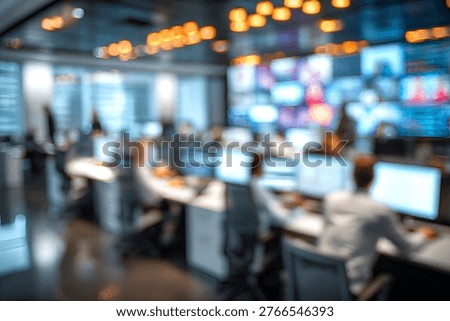 Abstract blurred background of a high-tech operations center, featuring numerous computer monitors displaying data and several individuals working at their desks, creating a dynamic and busy atmosphe.