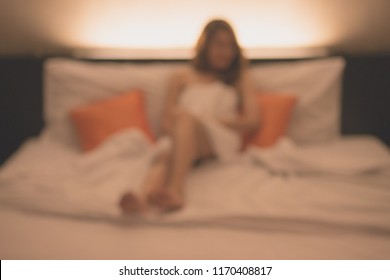 Abstract of blurred background image (defocus) of Prostitution woman sitting on the bed in hotel waiting for her customer. Conceptual image of Sexual services or Sex tourism.