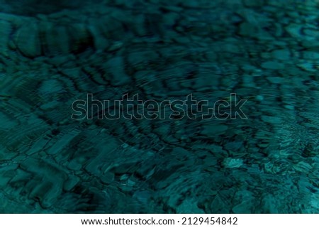 abstract blurred background - surface of a transparent clean blue water with circles from drops