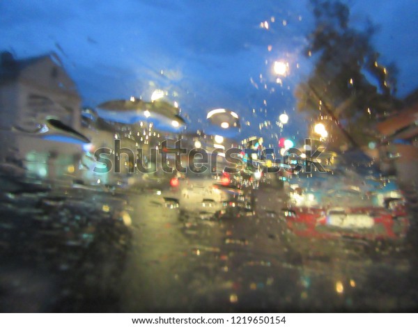  Abstract Blurred background, water drops on the\
windshield, traffic in the city on a rainy day, car windshield\
view, colorful bokeh. Street lights at night on a rainy day, Rain\
drop on the street