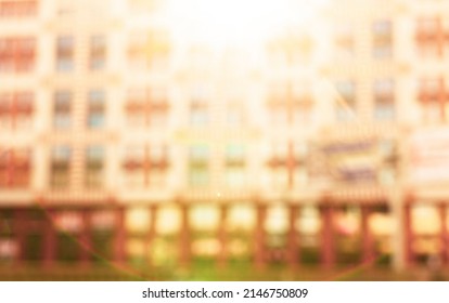 Abstract Blurred Building With Illuminated Facade Exterior At The Sunset. Blurry Modern Building With Bokeh Light And Defocused Dots With Sun Rays. Blur Windows Building For Background