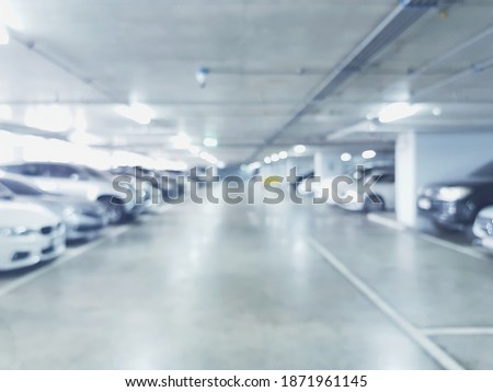 Abstract blurred cars parked in parking lot of shopping mall. Defocused background or backdrop for industrial and transportation concepts