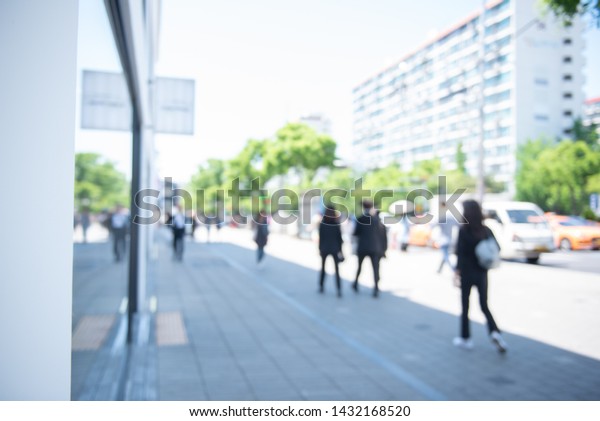 Abstract\
blurred of crowd people walking on sidewalk along the road in the\
business area in the city and modern style office buildings can be\
used for business background, urban\
scene