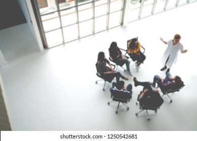 Abstract Blurred Defocused Of Asian Young Team Sitting Group Circle Meeting In Top Wide Angle View In Modern Office. Asian Speaker Explain, Teach, Coach, Sharing Idea To Audience In Education Concept.