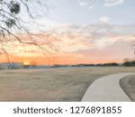 Abstract blurred dramatic sunset over urban park with grass lawn meadow and pathway near Dallas, Texas, USA