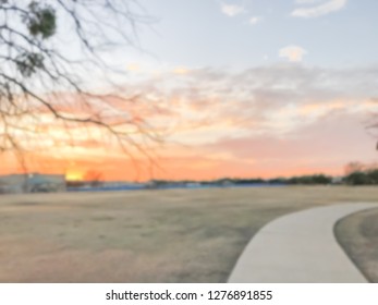 Abstract blurred dramatic sunset over urban park with grass lawn meadow and pathway near Dallas, Texas, USA