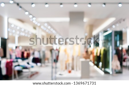Abstract blurred of fashion clothes shop boutique interior in shopping mall, with bokeh light background. Blurred image of mannequins inside a women fashion store.
