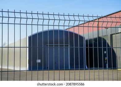 Abstract Blurred Gray Industrial Buildings Behind A Pvc Metal Fence Panel