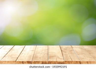 Abstract Blurred Green Bokeh And  Brown Wooden Tabletop Texture Perspective Counter For Promoting And Advertising Product On Display