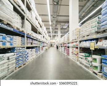 Abstract blurred hardware store aisle with finishing material shelves and unrecognizable customers as background