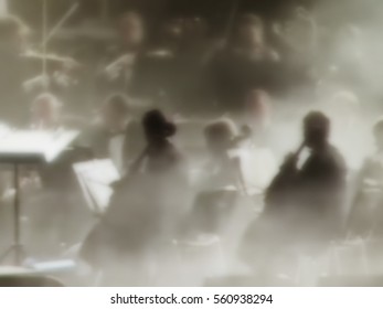 abstract blurred image. Artists symphony orchestra. Musician plays a musical instrument on the concert stage.  