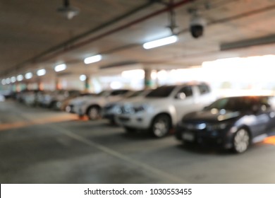 Abstract blurred image background of parking area, ground floor for car parking, Concrete skeleton interior design, Large private garage. shot in the evening with boken light from neon.