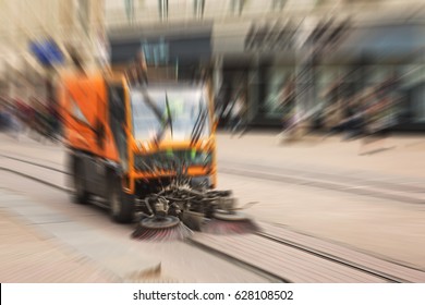 Abstract Blurred Image Of A Sweeper Vehicle Sweeping The Street Of The City On The Tram Railway, Defocused With Radial Blur In Post Production