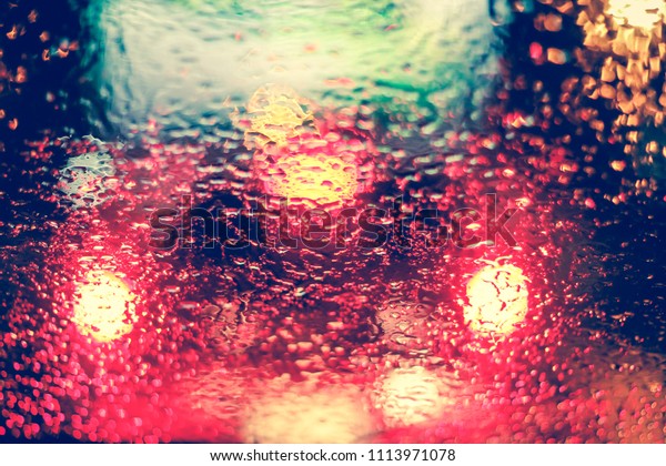 Abstract blurred Light traffic jam bokeh from\
inside a car view to outside road background while raining with\
rain drops on glass, night cityscape,cinematic photography vintage\
with film grain style.