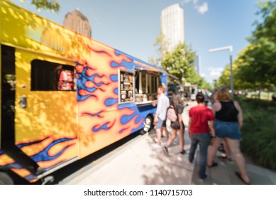 Abstract Blurred Motion Food Truck Vendor Customers Buy And Taste Variety Of Foods. People Waiting, Queuing In Line To Pick Up Lunch And Drink Delivery At Urban Park In Dallas, Texas, USA, Blue Sky