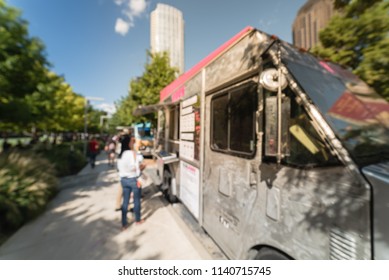 Abstract Blurred Motion Food Truck Vendor Customers Buy And Taste Variety Of Foods. People Waiting, Queuing In Line To Pick Up Lunch And Drink Delivery At Urban Park In Dallas, Texas, USA, Blue Sky