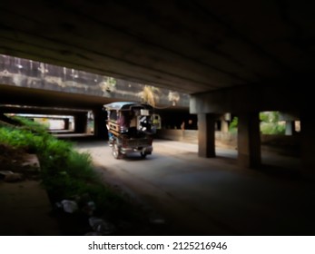 Abstract blurred photo of a tricycle running on the road under the underpass bridge