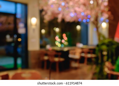 Abstract Blurred Shabu And BBQ Restaurant Interior With Empty Table Sets And Light Bokeh With Sakura Flower Tree.