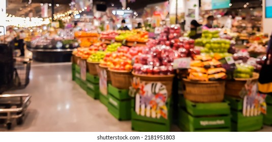 Abstract blurred supermarket aisle with colorful shelves fruit and unrecognizable customers as background.
