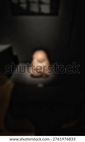 An abstract, blurry ancient object is dramatically spotlit in a dark museum or gallery exhibit.