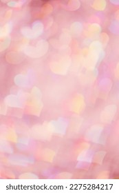 Abstract bokeh background pink color, natural flare from lights as hearts, pink monochrome vertical photo, optical effect, blurred bokeh texture as romance holiday backdrop, celebration screensaver